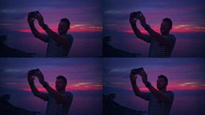 露台上浪漫的日落。男子用智能手机拍照