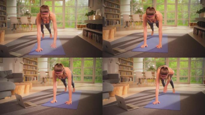女运动员用笔记本电脑在瑜伽垫上做木板。放松的家庭锻炼