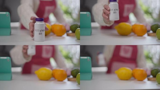 特写维生素D3药瓶放在桌子上，用高级高加索人的手拿走罐子。无法辨认的女性退休人员在家室内服药。健康和