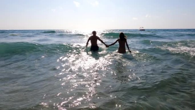 夫妇在热带海洋中跳跃。牵手，剪影视图