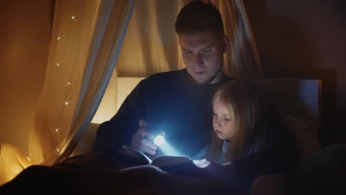 单身父亲正在黑暗的卧室里给他的小女儿读童话故事，幸福的家庭