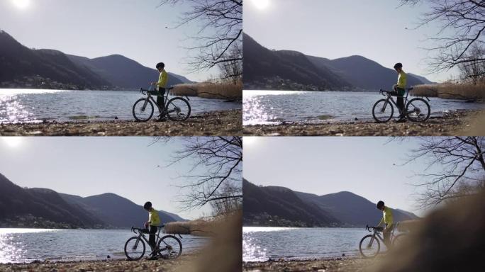 骑自行车的人停下来，在阳光明媚的日子里看着湖景