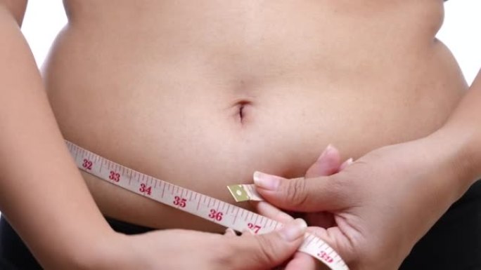 超重的女人测量她的腹部