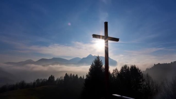 基督十字架在阳光照耀下，山景在云端之上