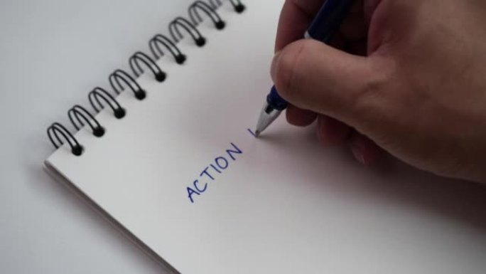 商人在家里或办公室的笔记本上使用蓝色墨水中性笔书写行动计划清单，选择性聚焦4k分辨率，顶视图。成功概