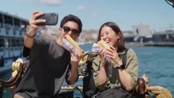 旅游夫妇在旅行中体验和吃街头美食时用智能手机自拍
