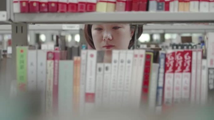 女人从书架上挑书图书馆空镜大学生校园生活