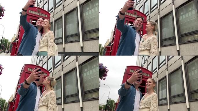 可爱的高加索夫妇在英国伦敦旅游时，在一个标志性的旅游红色电话亭一起自拍