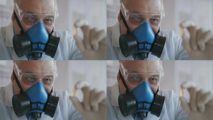 一位戴着蓝色呼吸器和防护眼镜的科学家的极端特写镜头，他开发了一种冠状病毒疫苗，里面装有白色药丸。医生