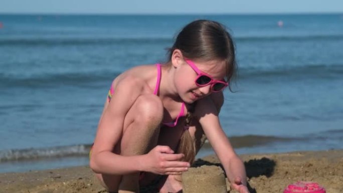 在海边或海边的热带海滩上玩耍的小女孩建造沙堡