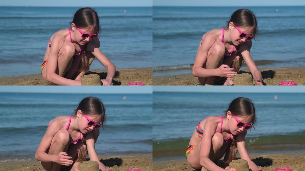 在海边或海边的热带海滩上玩耍的小女孩建造沙堡