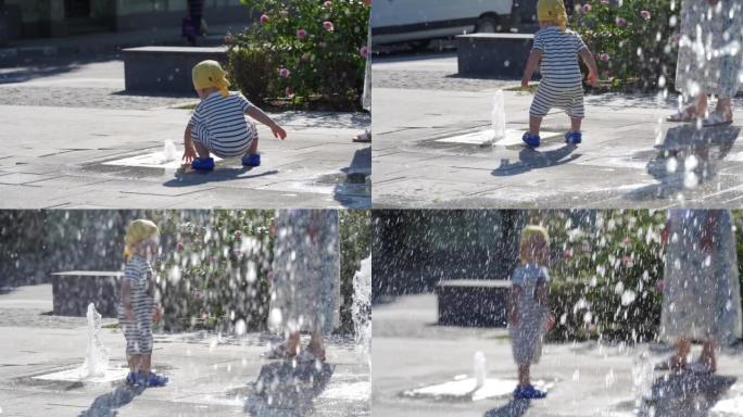 快乐的孩子和他的母亲在阳光明媚的夏日在公园的喷泉里玩得开心。1.5岁的孩子在热天玩喷泉水。
