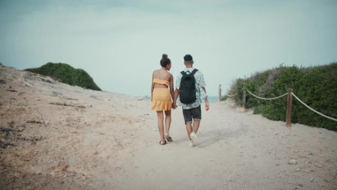 慈爱的非洲族裔夫妇牵手。在海滩上浪漫散步