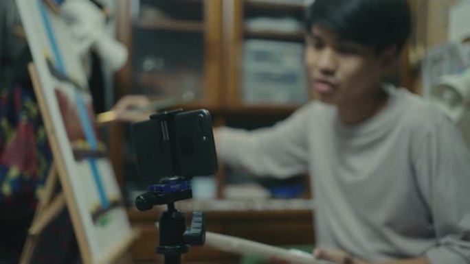 年轻的艺术家用智能手机直播视频绘画