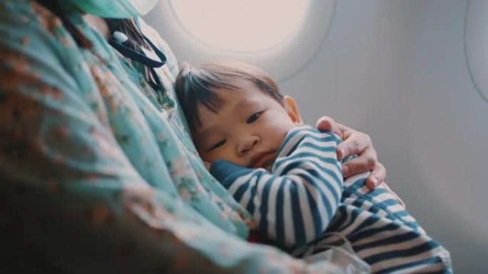 乘飞机旅行时，男孩睡在母亲的怀里。