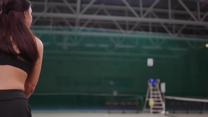 年轻的女网球运动员在室内球场上打球，用网球拍击球，在区域内奔跑