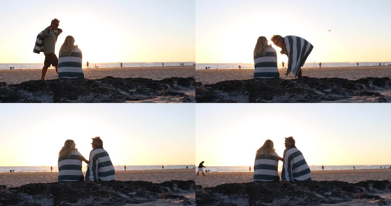 日落时分，情侣在安静的海滩上的毛巾下放松