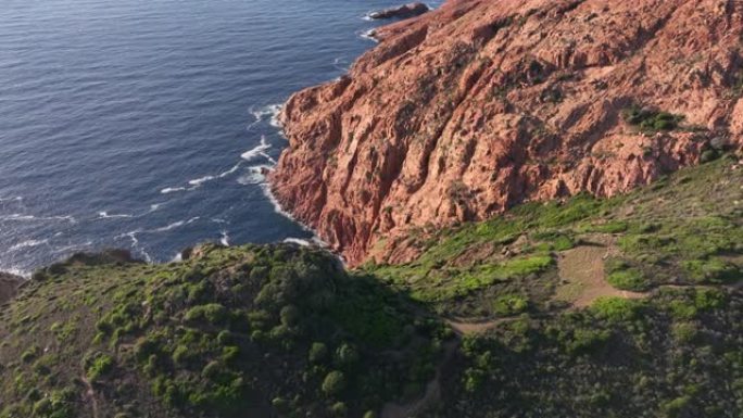 日落时飞越多山的海岸线，可以看到大海、悬崖和绿色的田野。