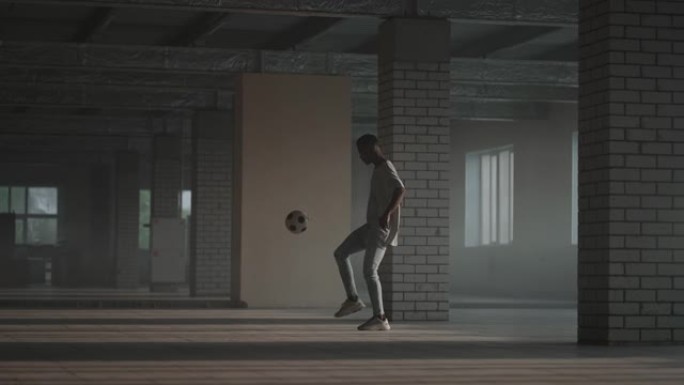 黑人男孩足球运动员在空旷的停车场内练习技巧，踢球和移动。慢动作城市生活方式