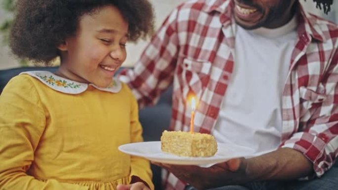 小女孩吹生日蛋糕蜡烛由爱心爸爸赠送，家庭假期