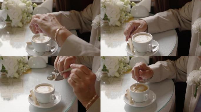 人的手打破糖棒，将糖滴入卡布奇诺咖啡中，搅拌咖啡