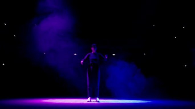 神秘的舞蹈表演在黑暗的舞台上，在蓝色的灯光下，女人在缓慢地移动