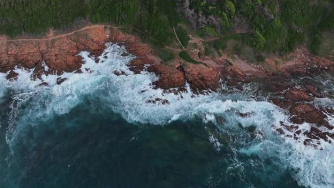 湛蓝海水的鸟瞰图，海浪冲入绿色的草地海岸线