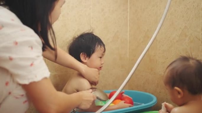 母亲正在家里的浴室给两个儿子洗澡。