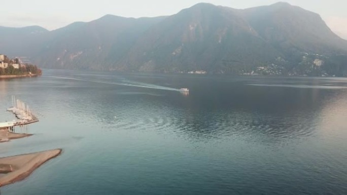 日落时用船拍摄卢加诺湖的空中无人机