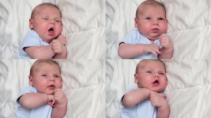 白色毯子上新生婴儿的特写肖像。软聚焦。婴儿在撒谎，打哈欠。一，两周大。女婴在家床上醒来。新生活和成长