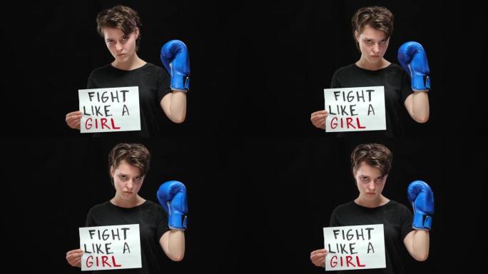 自信的严肃的女人在拳击手套中像女孩一样看着相机。自信的高加索女性活动家在黑色背景下为争取平等人权而战