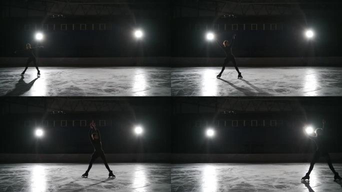 溜冰者在黑暗中的室内冰场用聚光灯训练。在体育场进行单人花样滑冰。女孩表演花样滑冰元素传播老鹰