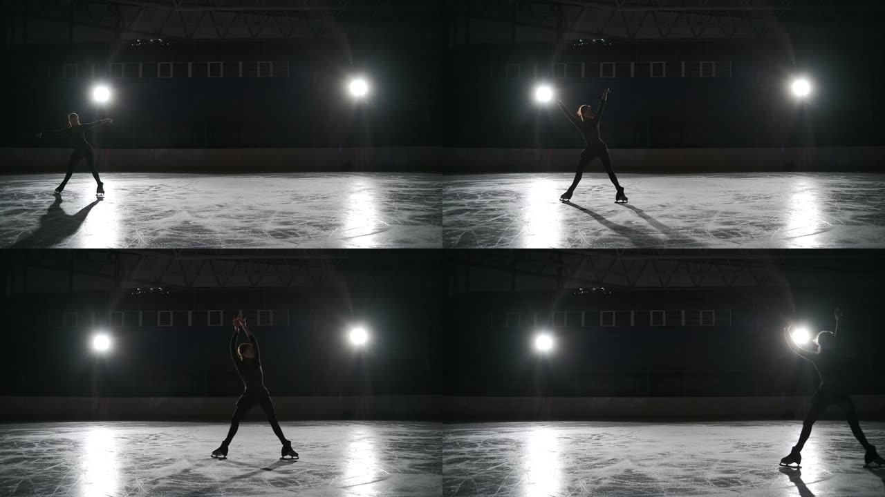 溜冰者在黑暗中的室内冰场用聚光灯训练。在体育场进行单人花样滑冰。女孩表演花样滑冰元素传播老鹰