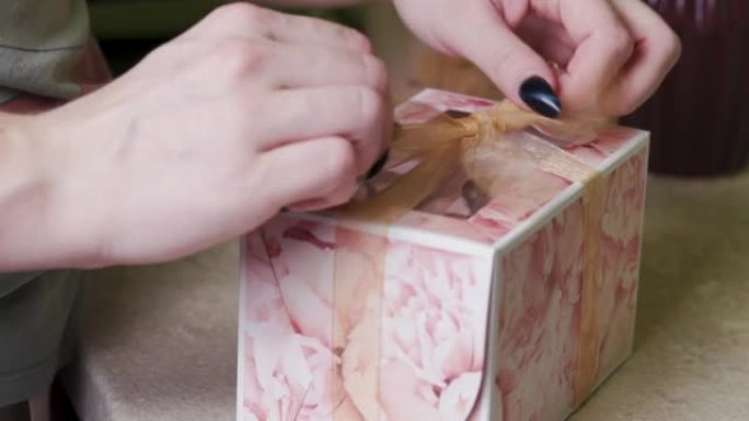 一个糕点厨师女孩用纸杯蛋糕在礼品盒上系一个蝴蝶结。
