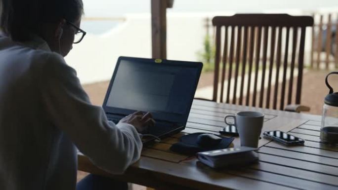 女人在海景阳台上用笔记本电脑工作