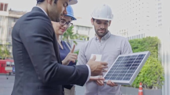 一群商人和会议工程师在建筑中安装太阳能电池板。建设环保建筑结构咨询团队。就施工队的工作交换意见。