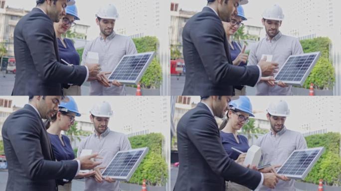 一群商人和会议工程师在建筑中安装太阳能电池板。建设环保建筑结构咨询团队。就施工队的工作交换意见。