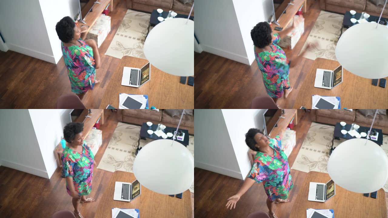 在虚拟的欢乐时光里，快乐的女人在笔记本电脑前在家跳舞