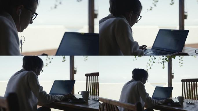 女人在海景阳台上用笔记本电脑工作。纵断面视图