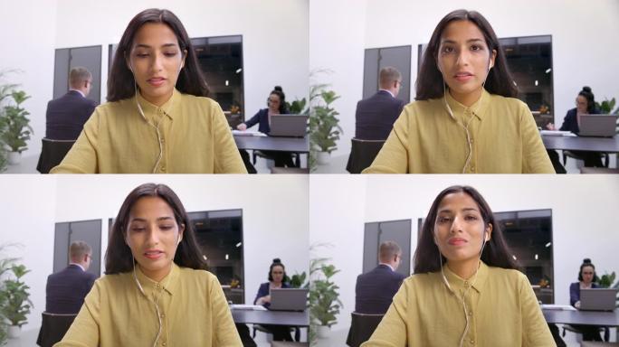 坐在办公室的LD印度妇女在视频会议上打字和听