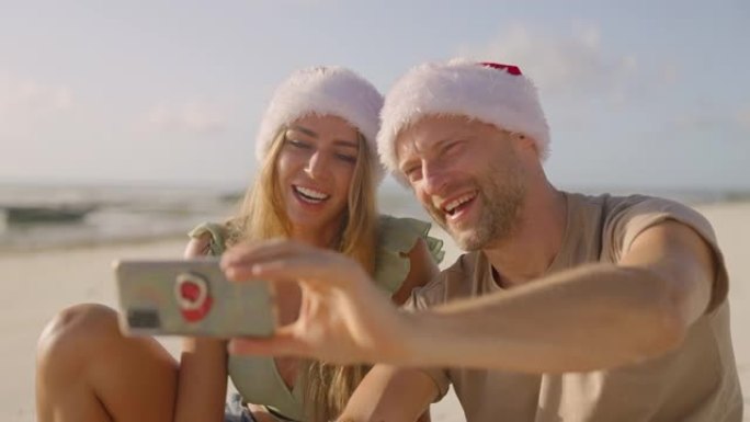 夏季圣诞问候。夫妇微笑着向智能手机挥手