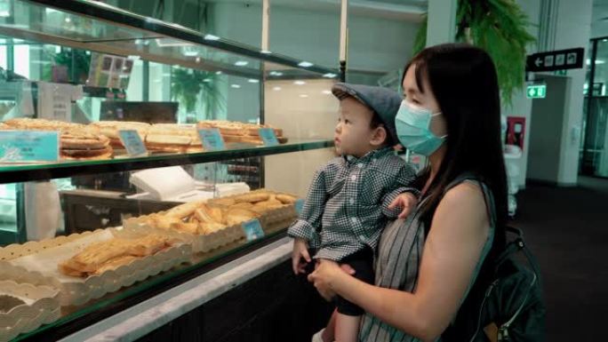 迷人的年轻母亲正在机场选择面包
