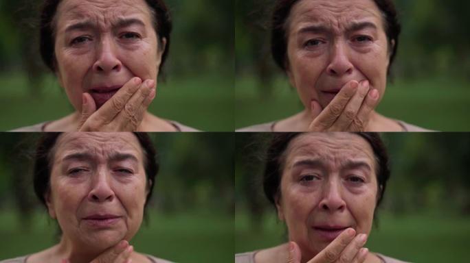 头像肖像哭泣绝望沮丧的高加索高级妇女用手闭上脸。特写悲伤绝望的女性退休人员看着公园户外摆姿势的相机。