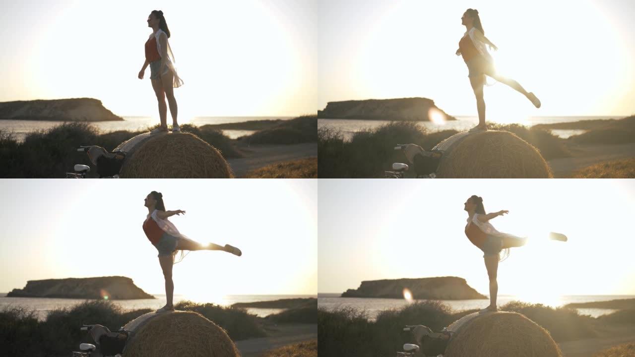 苗条的幸福女人模仿飞鸟站在阳光中的黄色小麦堆上。在塞浦路斯风景的背景下，在户外阳光普照的白人年轻女士