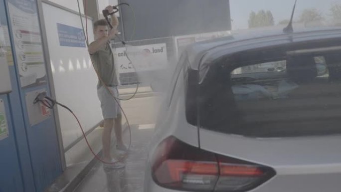 一名男子在洗车场用肥皂水洗车