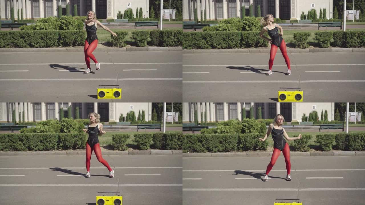 自信苗条的女人在城市道路上20世纪80年代做体操或有氧运动。快乐的年轻白人妇女的肖像随着黄色录音机的