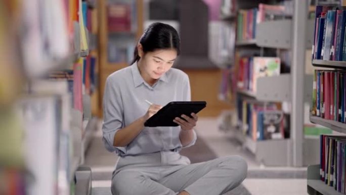 在亚洲的大学图书馆，亚洲女性正在通过图书馆的平板电脑搜索互联网。