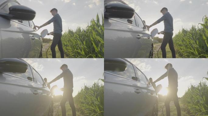 日落时分，男子站在玉米地，为电动汽车充电
