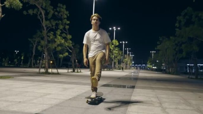 亚洲青年男子在夜城溜冰场滑板