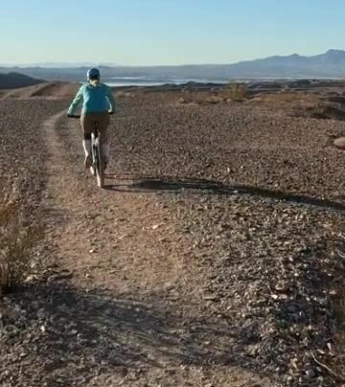 女性山地自行车手沿着沙漠小路